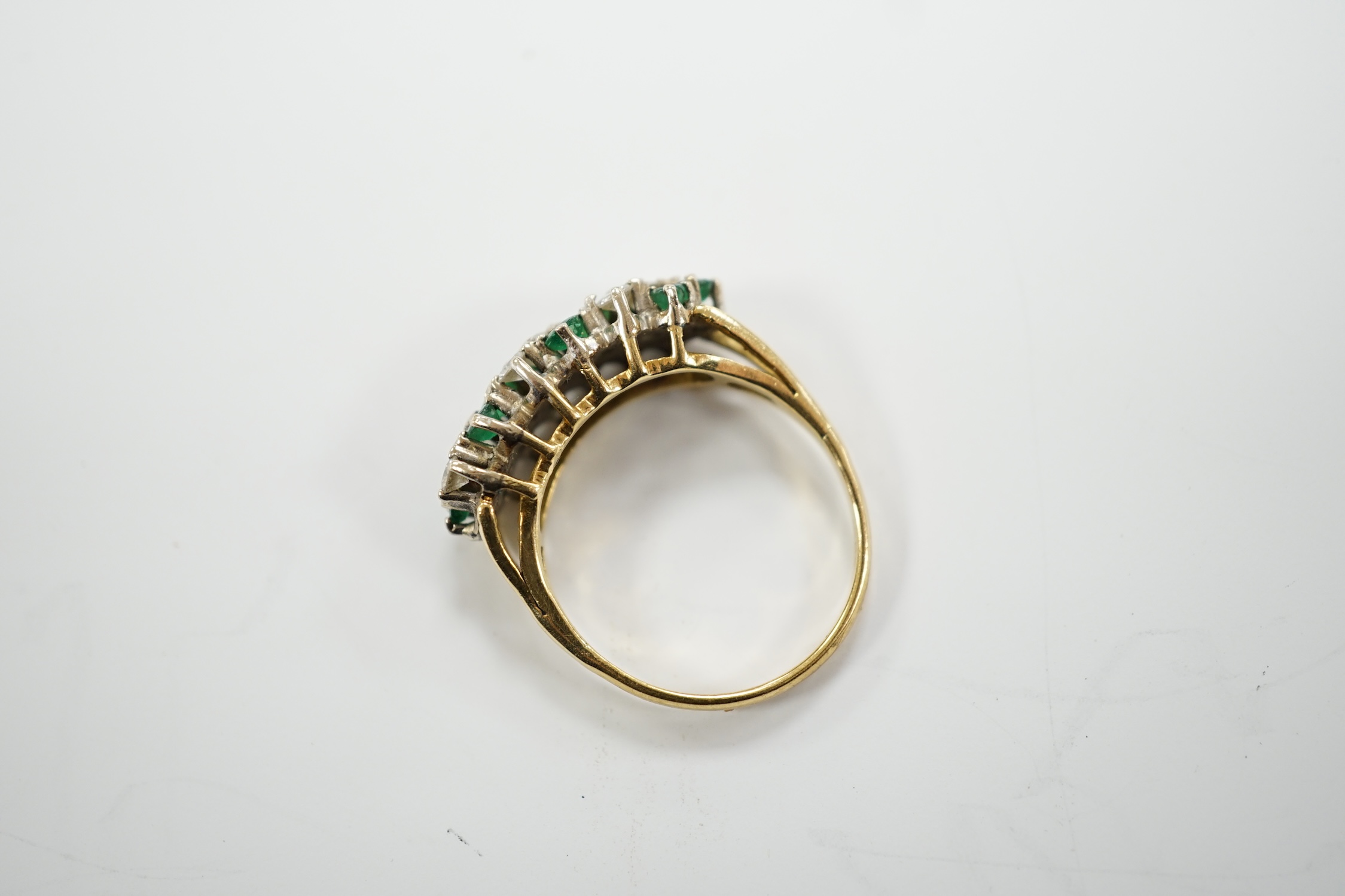 A modern 18ct, emerald and diamond set cluster half hoop ring, size O, gross weight 4.9 grams.